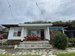 a house with a table and chairs on the porch at Wel home stay in Pulau Gilimota