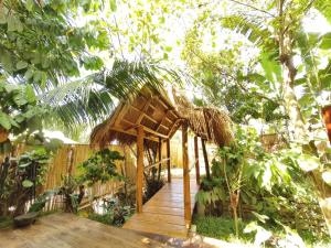 a wooden walkway in a garden with a hut at Terracotta tropical nest in San Vicente