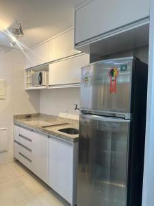 a kitchen with a stainless steel refrigerator and white cabinets at Flat Lounge 22 Setor Oeste in Goiânia