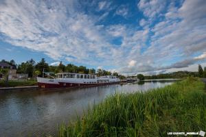a couple of boats are docked on a river at Au relais in Sarralbe