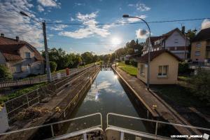 a canal in the middle of a street with houses at Au relais in Sarralbe