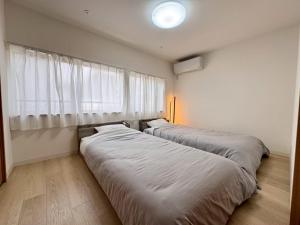 two beds in a room with a window at ura BETTEi 別邸 in Okayama