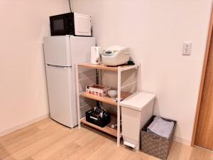 a kitchen with a white refrigerator and a microwave at ura BETTEi 別邸 in Okayama