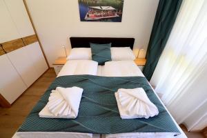 two beds in a room with green sheets and pillows at Premium Apartments am Weißensee in Weissensee