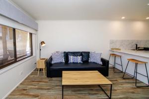 a living room with a black couch and a table at Bank's Place in Yarrawonga