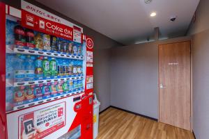 a red soda machine in a room with a door at HOTEL R9 The Yard Namerikawa in Namerikawa