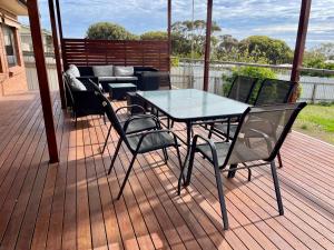 a patio with a table and chairs on a deck at Brindy's By the Bay in Emu Bay