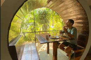 a man sitting at a table in a room with a window at Tubo Tulum Hostel - Unique Stay in Tulum