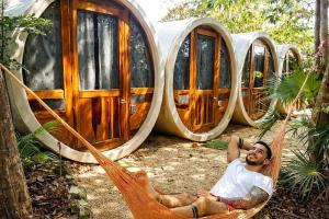 a man laying in a hammock in front of a group of barrels at Tubo Tulum Hostel - Unique Stay in Tulum