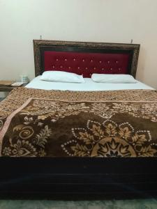 a bed with a brown and white bedspread on it at Al Shahzan Hotel in Lahore