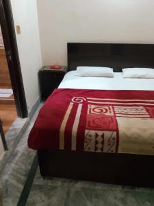 a bedroom with a bed with a red blanket at Al Shahzan Hotel in Lahore