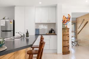 a kitchen with white cabinets and a black counter top at Pet Friendly Beachside Hideaway - Lazy on Lowry in Woorim +11 photos