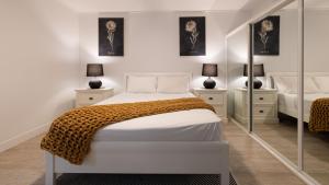 a white bedroom with two beds and two mirrors at Waterline Direct Poolside Apartment in Agnes Water