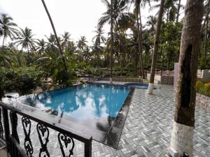 a large swimming pool in a resort with palm trees at Sanoraaa Resort in Dabolim