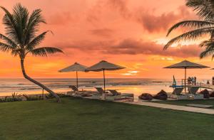 a sunset at the beach with chairs and umbrellas at Bali Beach Glamping in Tabanan
