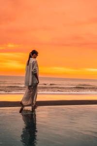 a woman walking on the beach at sunset at Bali Beach Glamping in Tabanan