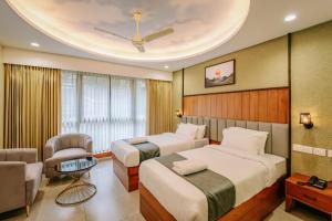 two beds in a hotel room with a ceiling at Hotel Morya Suites IGI Airport in New Delhi