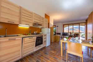 a large kitchen with wooden cabinets and a table at Sunset in Ranco: Lakeview Townhouse with Private Garden - Happy Rentals in Ranco