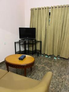a living room with a couch and a table and a tv at VallabhanAnnexHomestay in Varkala