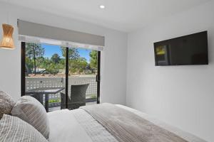 a bedroom with a bed and a flat screen tv at Orford Waterfront Cottage in Orford