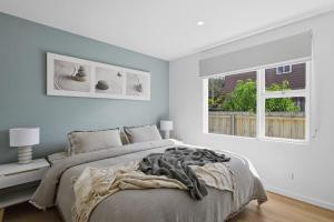 a white bedroom with a bed and two windows at Orford Waterfront Cottage in Orford