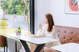 a woman sitting at a table with a plate of food at The Muse Hotel 1 in Ðố Sơn