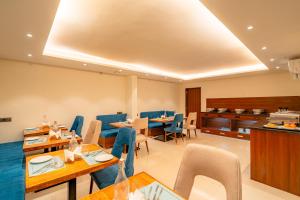 a restaurant with blue chairs and tables and a kitchen at Playsales SSR in Indore