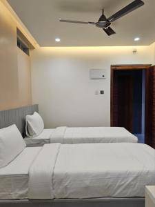 two beds in a bedroom with a ceiling fan at Babus Serviced Apartments in Coimbatore