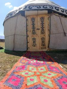 a rug in front of a yurt with a door at eco house "QUMUSH YURT" in Emgekchil