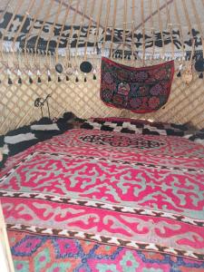 a bed with a colorful rug on top of it at eco house "QUMUSH YURT" in Emgekchil