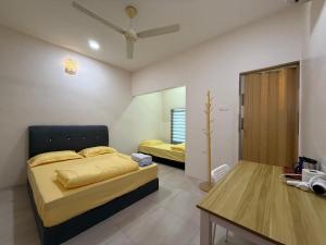 a bedroom with two beds and a table in it at Ipoh TZY's Homestay in Ipoh