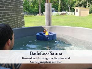 a man in a bird bath with a toy in the water at Fewo River, Stilvolles Ferienhaus für Familien großer Garten, Spielplatz, Sauna & Badefass in Wendisch Rietz