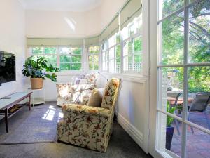 a living room with a chair and a table and windows at The old Chiltern bank BnB in Chiltern +6 photos