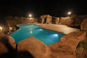 a swimming pool with a rock wall around it at night at Crystal Falls Wayanad in Wayanad