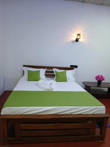 a bedroom with a large bed with green and white pillows at Canal Resort Udawalawa in Ratkarawwa