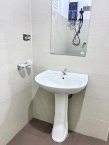 a bathroom with a white sink and a mirror at Amani Rooms in Panadura