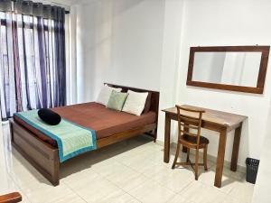 a small bedroom with a bed and a table at Amani Rooms in Panadura