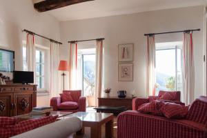 een woonkamer met rode stoelen en een tafel en ramen bij Casa degli Olivi in Levanto