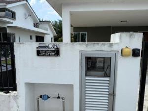 a white wall with a door in front of a house at Teratak Shamar in Kampong Tebok Pulai +2 photos