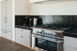 a kitchen with a stainless steel stove and white cabinets at Blacksmith House on Main in Tocumwal