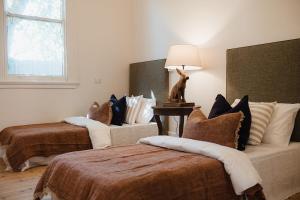 a room with two beds with pillows and a lamp at Blacksmith House on Main in Tocumwal