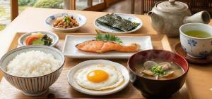 a wooden table with plates of food and bowls of food at エスエスビーホテル滄浪 in Satsumasendai