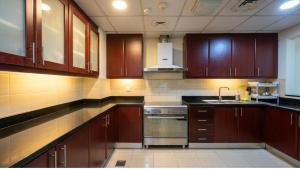 a kitchen with wooden cabinets and a stainless steel oven at Devine Holidays JBR in Dubai