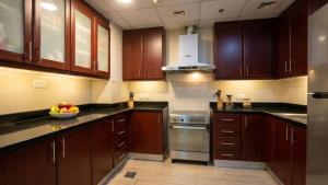 a kitchen with wooden cabinets and a bowl of fruit on the counter at Devine Holidays JBR in Dubai