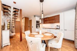 a kitchen with a wooden table and white chairs at Sunset Stay Pärnu in Pärnu