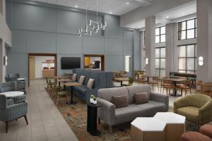 a waiting room with couches and tables and a tv at Hampton Inn & Suites Phoenix Glendale-Westgate in Glendale