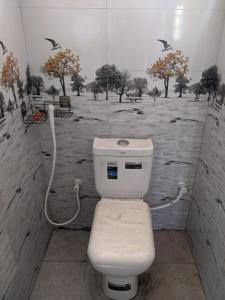 a bathroom with a toilet with a painting on the wall at flying in stay in Dankotuwa