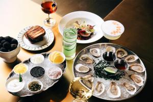 a table with plates of oysters and glasses of wine at Hotel Savoy Kansas City, Tapestry Collection by Hilton in Kansas City