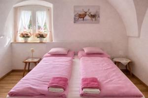 two beds in a room with pink sheets at La Busa dai Zervi in Daiano