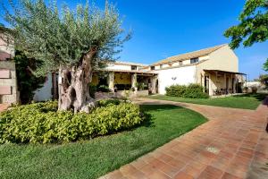 une maison avec un arbre et une allée en briques dans l'établissement Hotel Villa Giulia, à Marzamemi